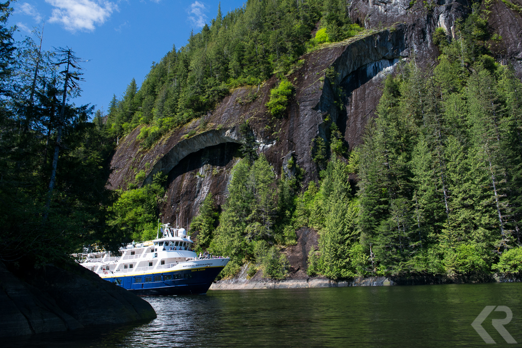 A small ship passes through a narrow passage in Alaska.